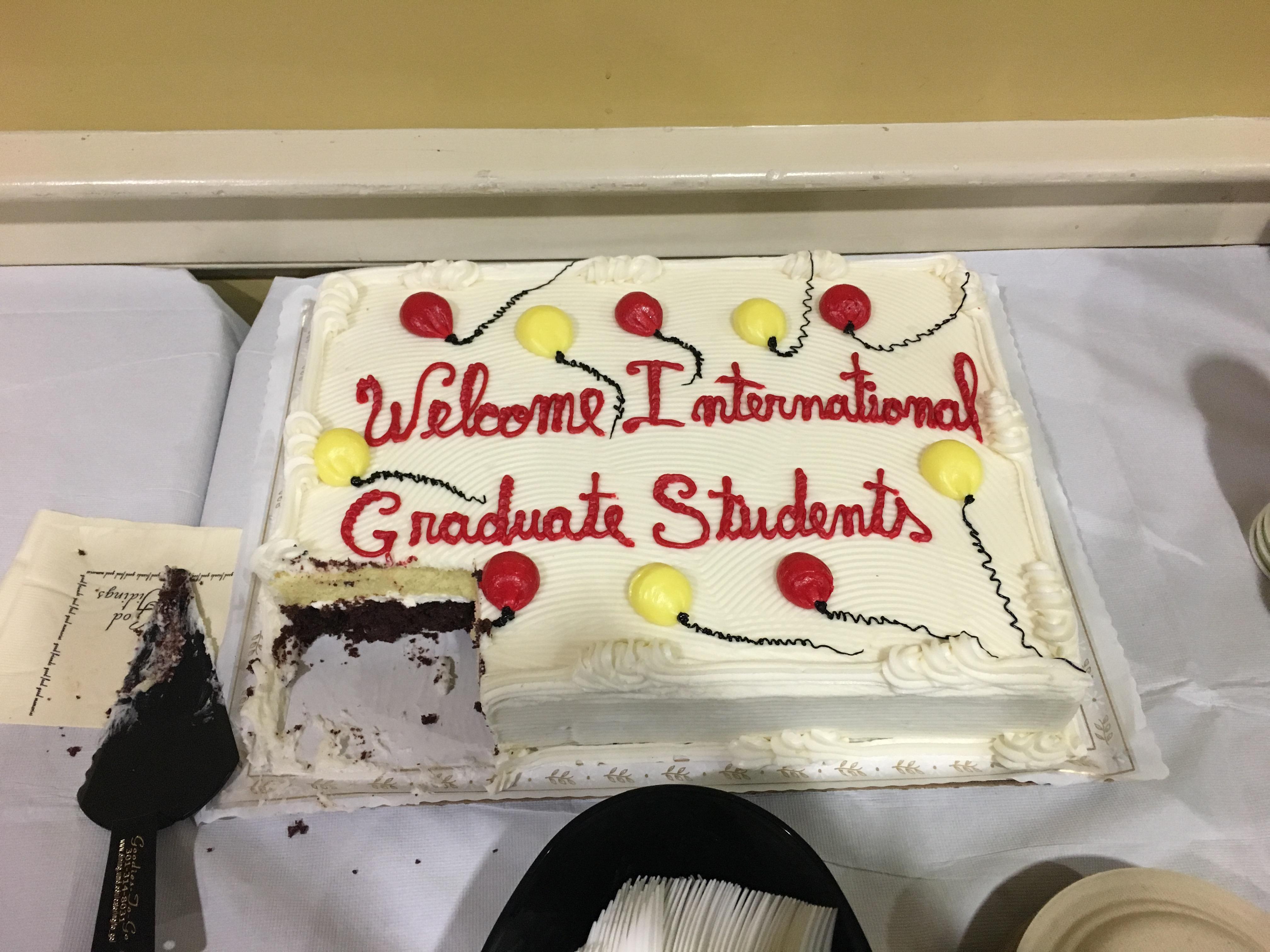 Sheet caked decorated with frosting balloons and the words "Welcome International Graduate Students"