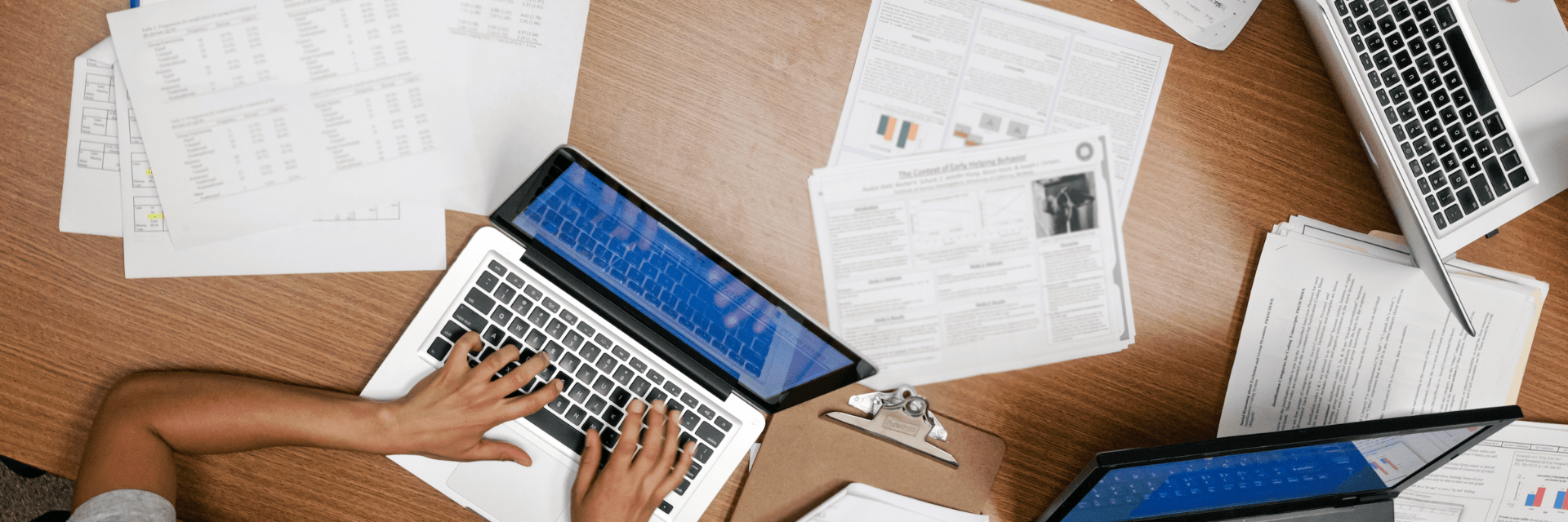 over the head shot of hands on a laptop and papers on a desk